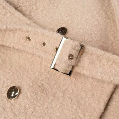 Close-up of a beige fabric surface with metal buttons and a rectangular metal clip.
