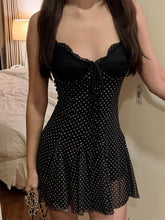 Woman wearing a black polka dot dress in a bedroom setting