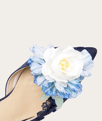 Navy high-heeled shoe with a large white and blue floral decoration on a light background