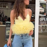 Woman wearing a yellow fluffy top and blue jeans in a cafe setting