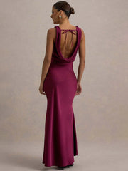 Woman wearing a burgundy evening gown with a open back design on a neutral background