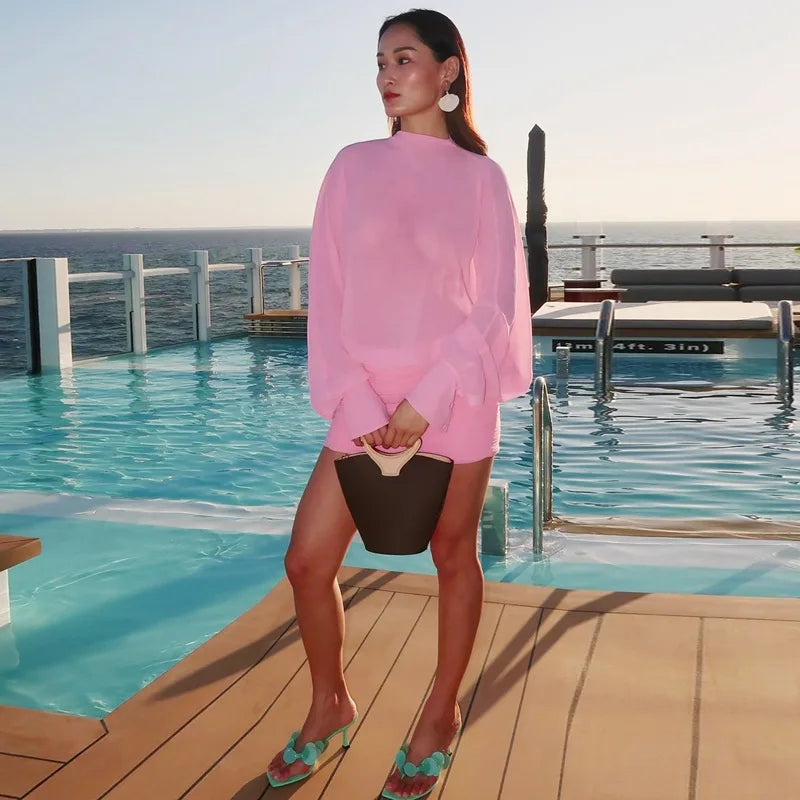 Woman in a pink outfit standing by a pool with ocean view