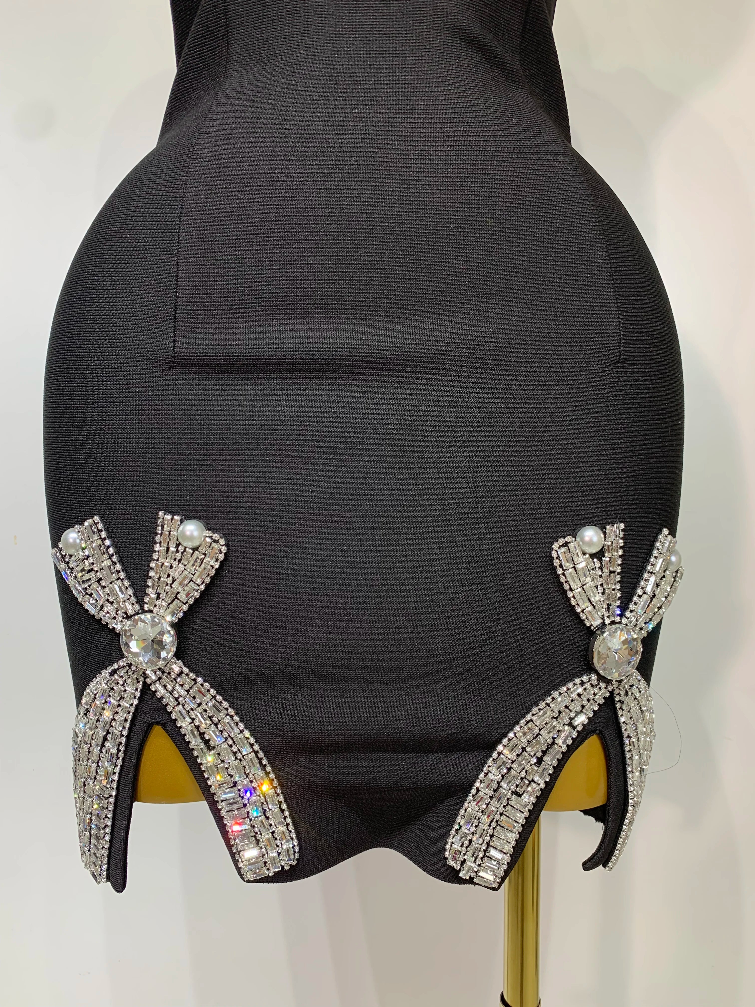 Black high-heeled shoes with decorative bows on a mannequin.