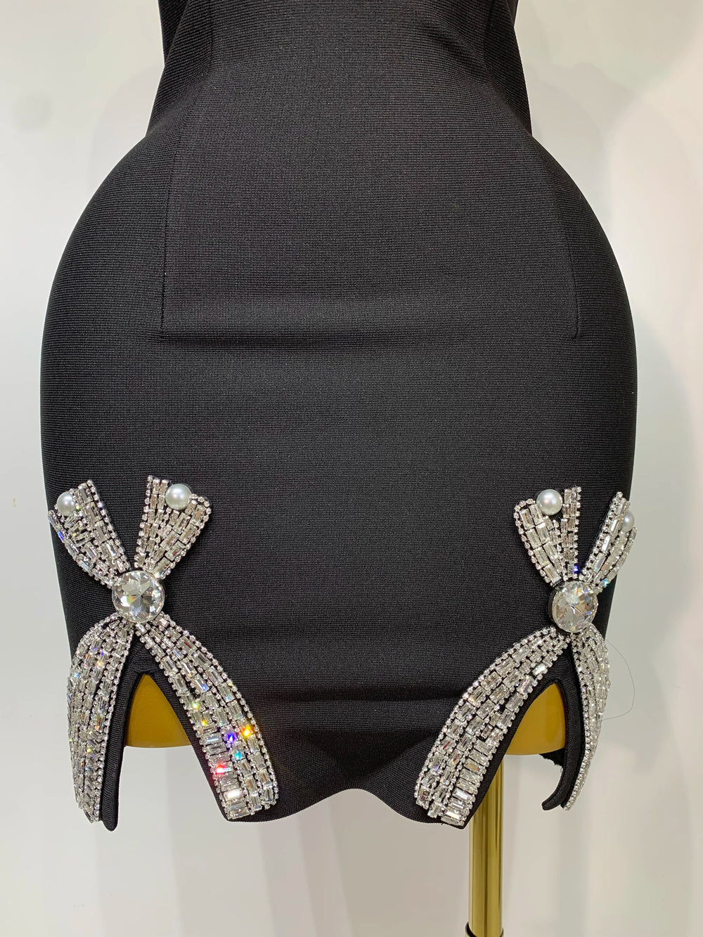 Black high-heeled shoes with decorative bows on a mannequin.