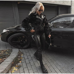 Person in black leather outfit standing next to a black car