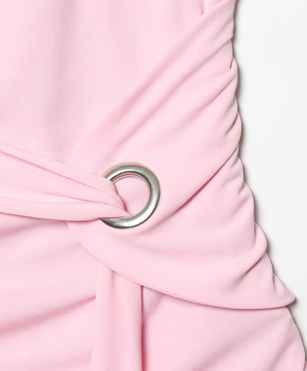 Close-up of a pink dress with a silver buckle on a light pink background