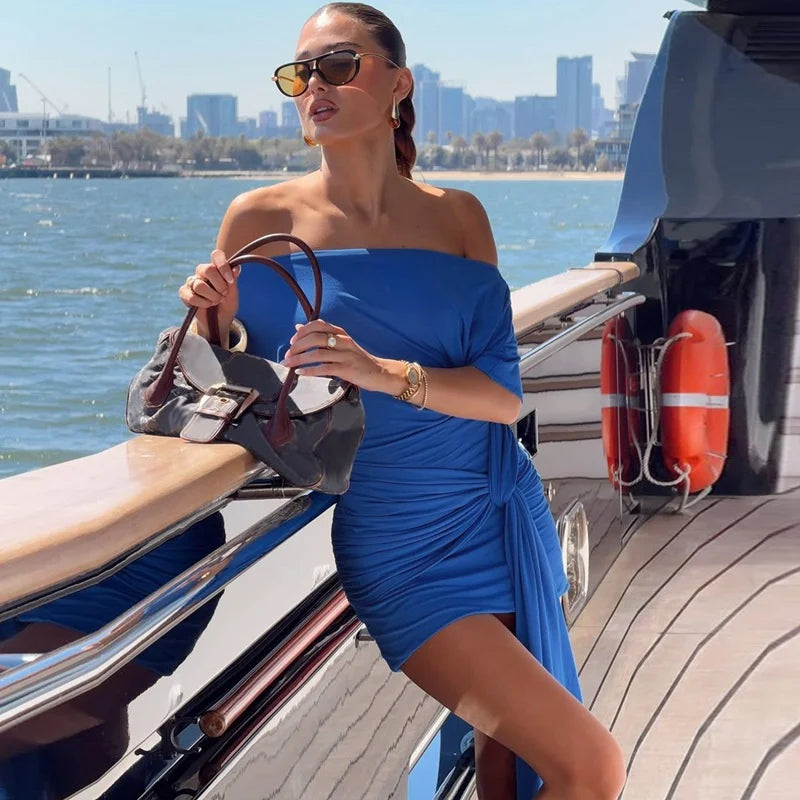 Woman in a blue dress on a boat with a city skyline in the background