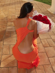 Woman in an orange dress holding a bouquet of red flowers on a tiled patio.