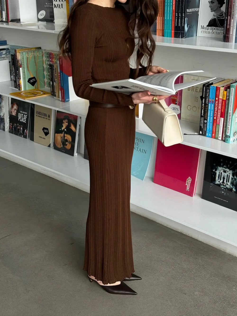 Woman in a brown dress reading a book in a library setting