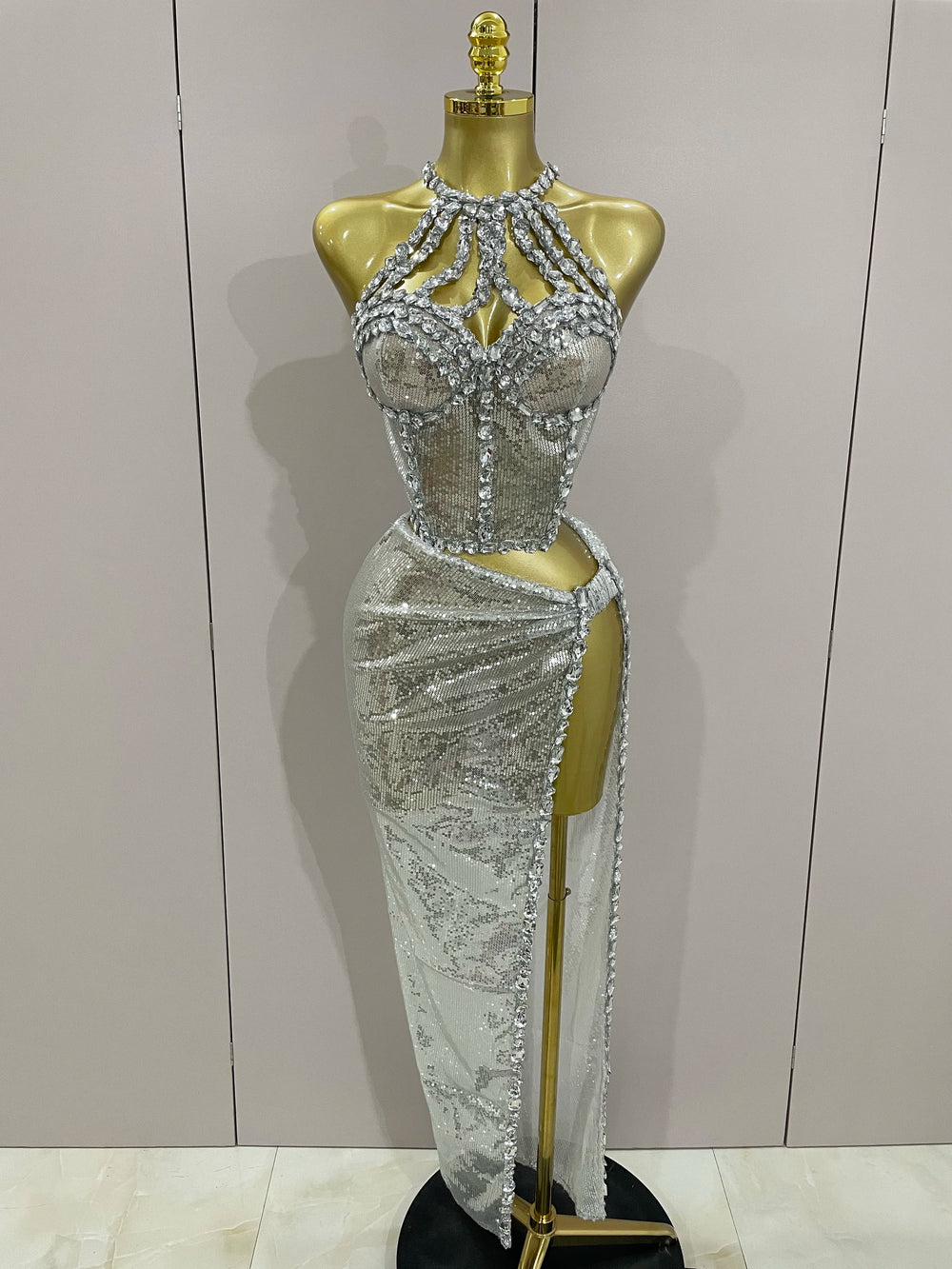 Silver beaded evening gown on a mannequin against a plain background