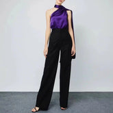 Person wearing a purple top and black pants on a plain background