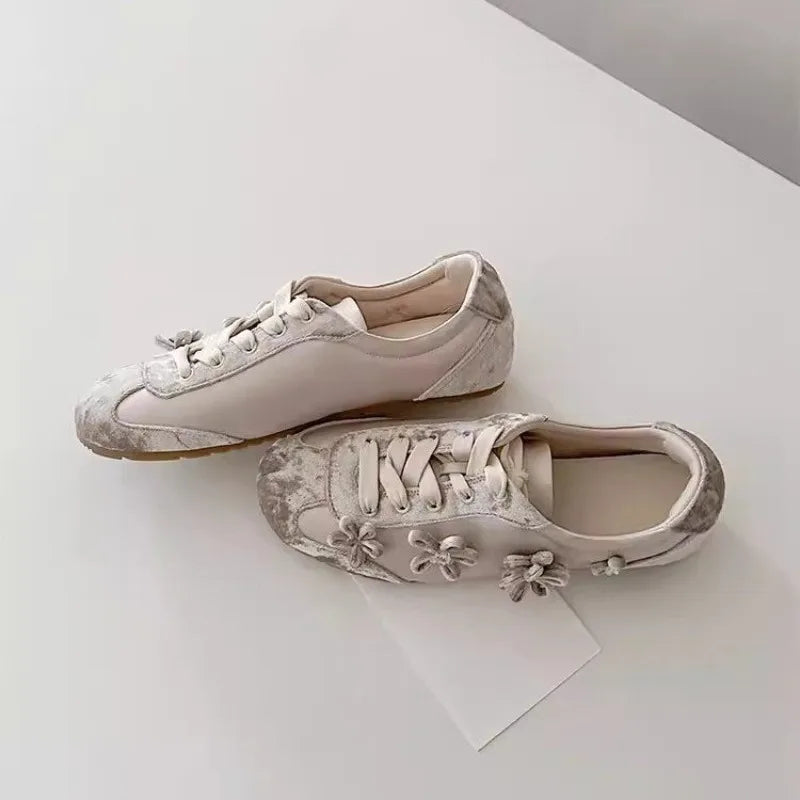 Pair of light grey sneakers with floral appliqu�s, shown from a side angle.