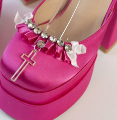 Pink high-heeled shoes with decorative elements on a light background