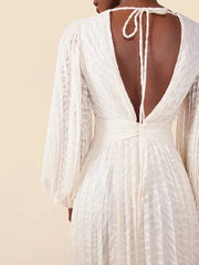 White dress with open back and long sleeves on a beige background