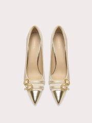 Gold high-heeled shoes with decorative straps on a light beige background