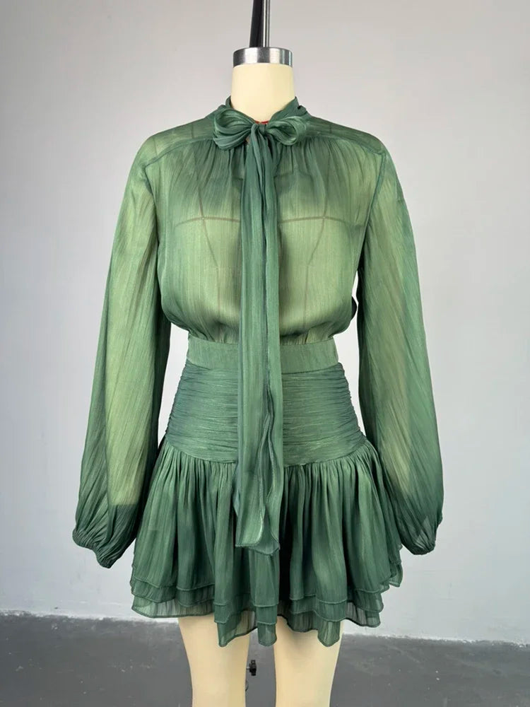 Green dress with long sleeves and a tie neckline on a mannequin against a gray background