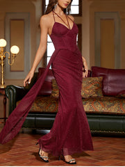 Woman wearing a burgundy evening gown in an elegant room with a lamp and sofa.