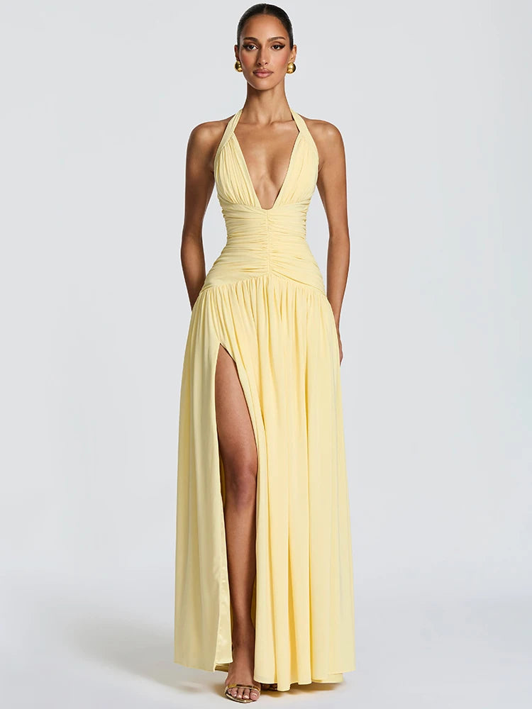 Woman wearing a yellow halter neck gown with a high slit on a white background