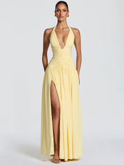 Woman wearing a yellow halter neck gown with a high slit on a white background