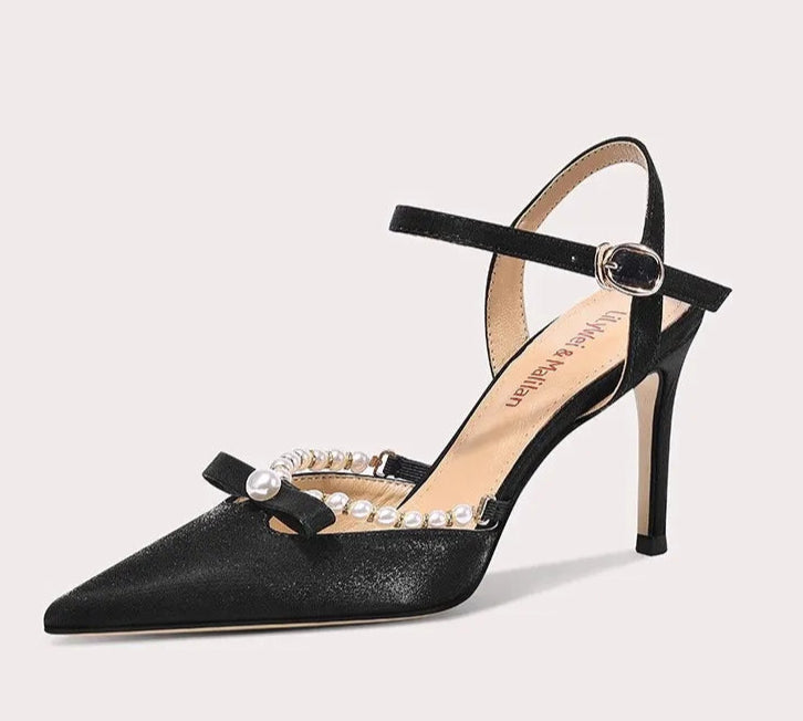 Black high-heeled shoe with pearl embellishments on a light gray background