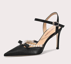 Black high-heeled shoe with pearl embellishments on a light gray background