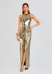 Woman wearing a metallic gold dress with a high slit on a light gray background