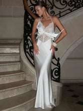 Woman in a white dress standing on a staircase with decorative railings.