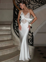 Woman in a white dress standing on a staircase with decorative railings.