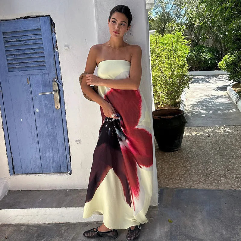 Woman in a strapless dress with a red and black floral pattern standing outdoors.