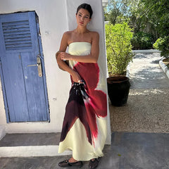 Woman in a strapless dress with a red and black floral pattern standing outdoors.