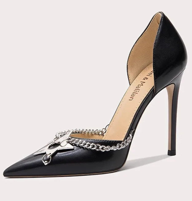 Black high-heeled shoe with chain detail on a light gray background
