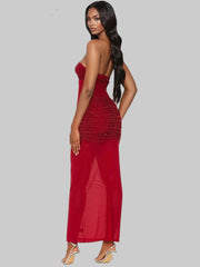 Woman wearing a red strapless dress with a slit on a gray background