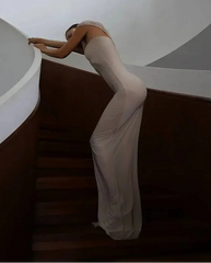 Person in a white dress standing on a staircase with a minimalistic background