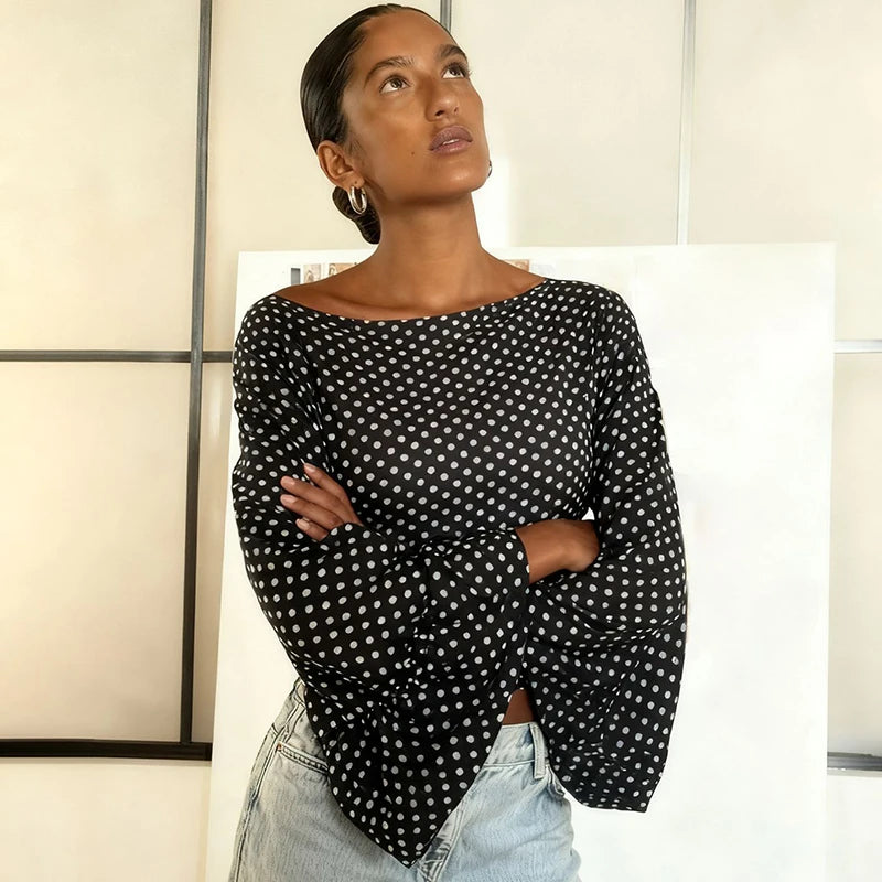 Woman wearing a black polka dot top with light blue jeans indoors.