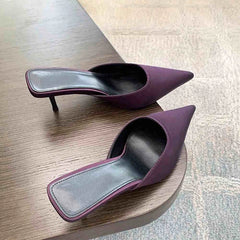 Pair of purple high-heeled shoes on a wooden surface.