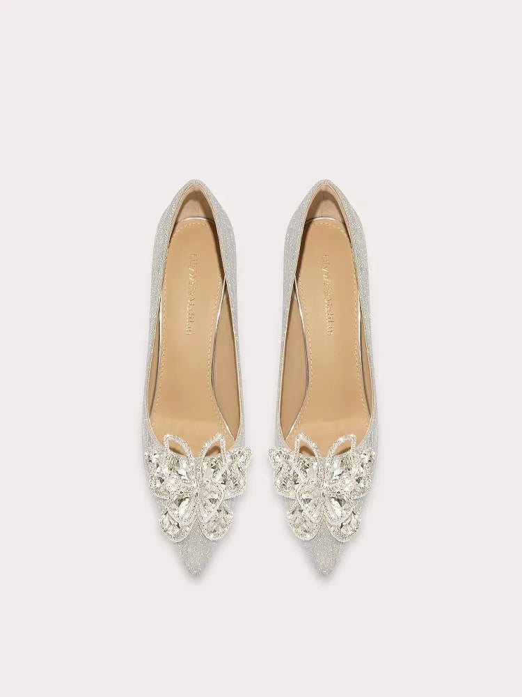 Pair of silver pointed-toe flats with crystal embellishments on a light gray background