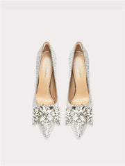 Pair of high-heeled shoes with crystal embellishments on a light gray background