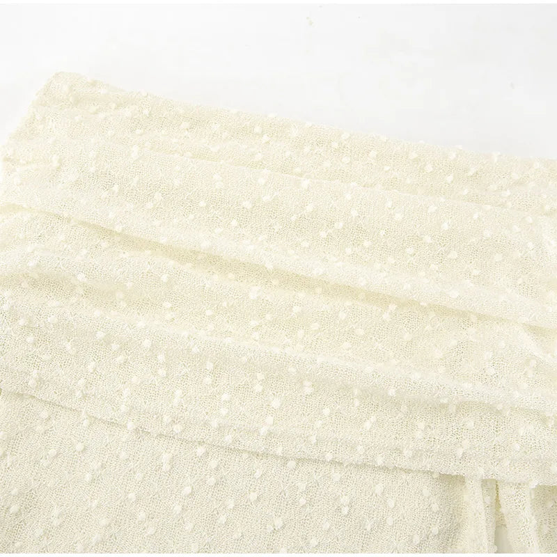 Close-up of a textured cream fabric with a subtle pattern on a white background