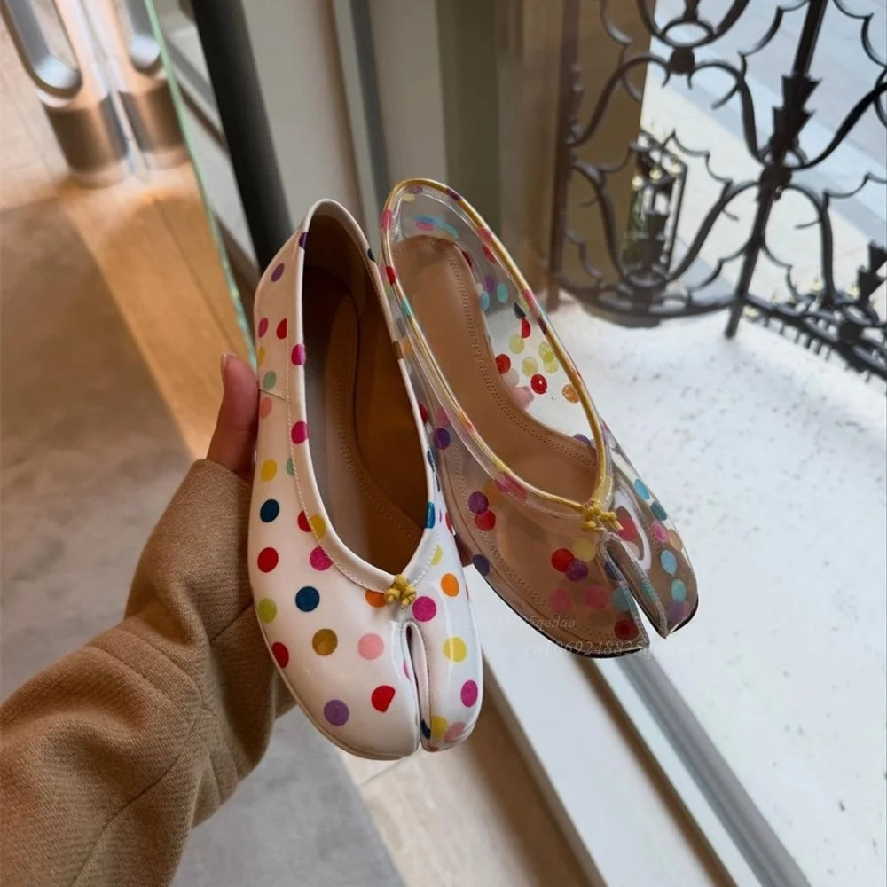 Hand holding a transparent and a patent polka dot split-toe flat