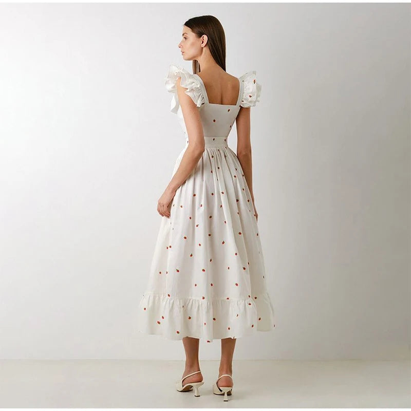 Woman wearing a white dress with floral details on a plain background