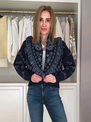 Woman wearing a dark blue patterned jacket in front of a wardrobe with white clothes.