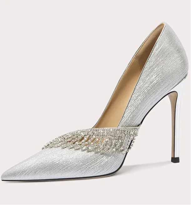 Silver high-heeled shoe with embellishments on a light gray background