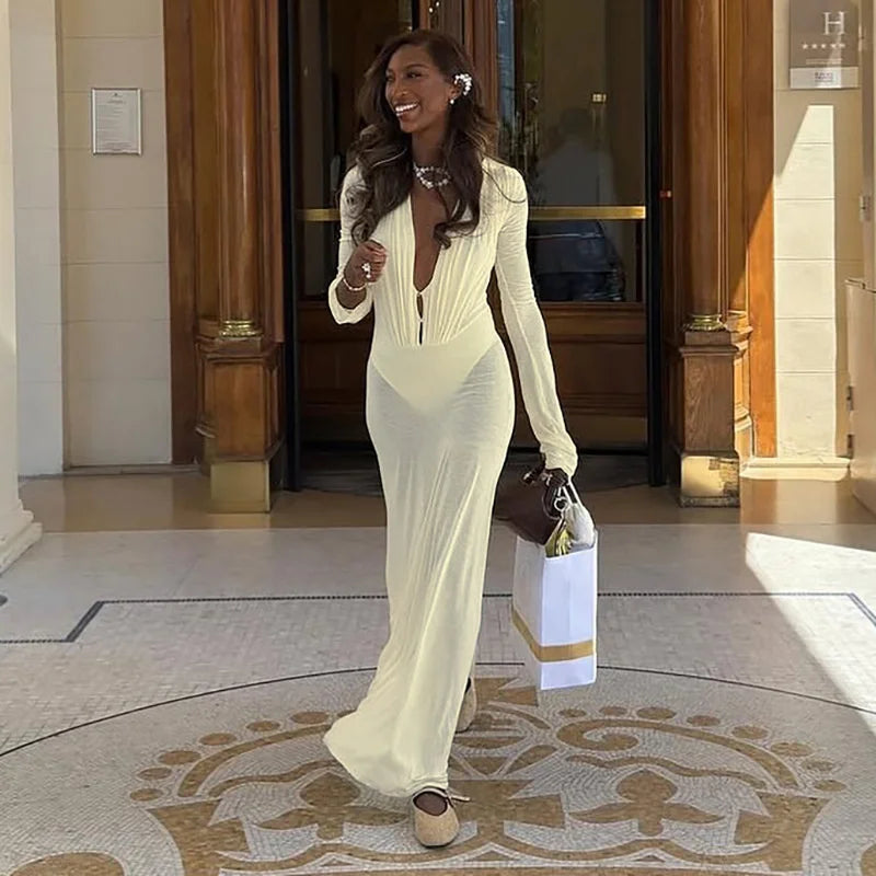 Woman in a white evening gown walking through a grand entrance.