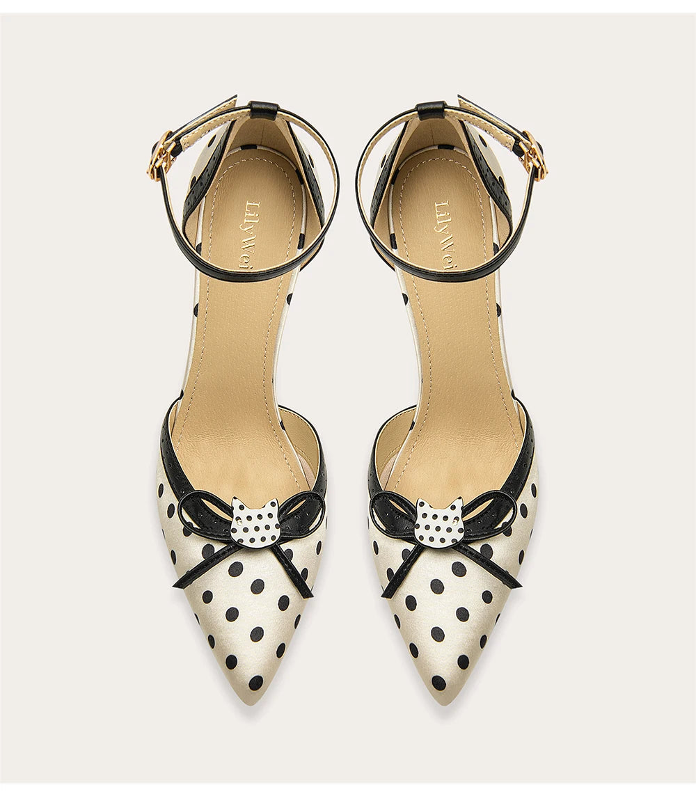 Pair of polka dot shoes with bow details on a light gray background
