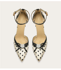 Pair of polka dot shoes with bow details on a light gray background