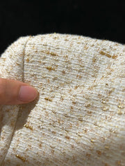 Close-up of textured fabric with gold specks and a finger for scale.