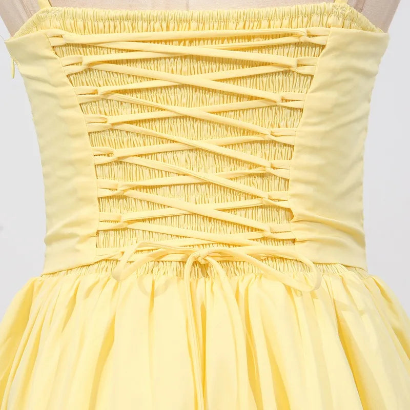 Yellow dress with criss-cross straps on a white background