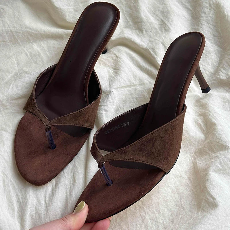 Pair of brown suede high-heeled sandals on a white fabric background