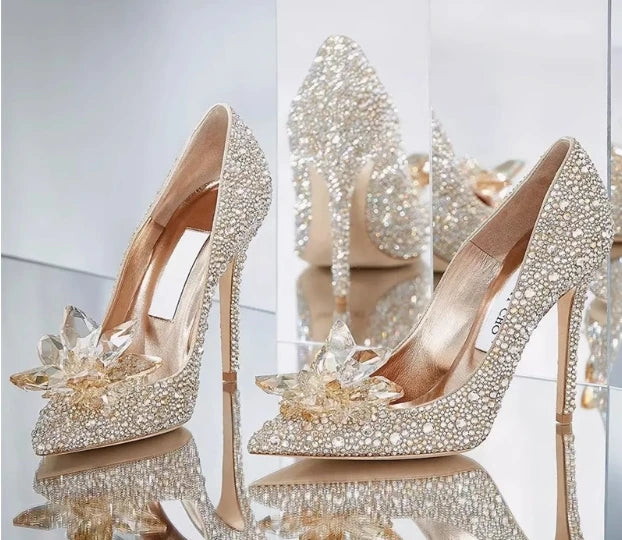 Sparkling high-heeled shoes with crystal embellishments on a reflective surface.