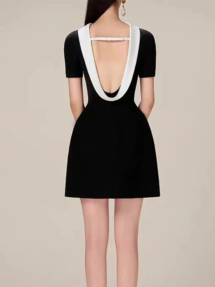Black dress with white trim on a plain background